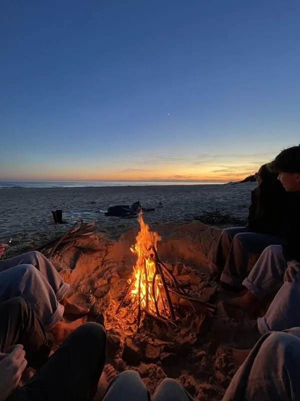 A beach bonfire beside the ocean at dusk