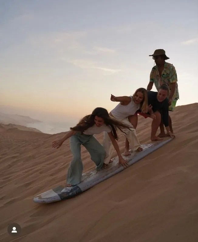 Friends sandboarding on the dunes